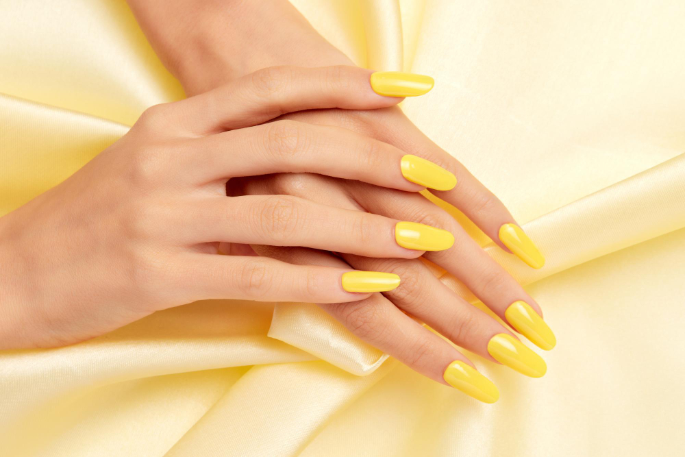 closeup-shot-female-s-hands-with-yellow-nail-polish-yellow-silk-fabric (1)